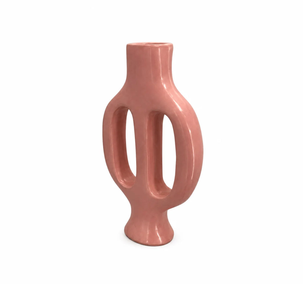 A modern, sculptural ceramic vase in a glossy dusty rose pink color, featuring two vertical looped handles and a flared base, set against a plain white background.