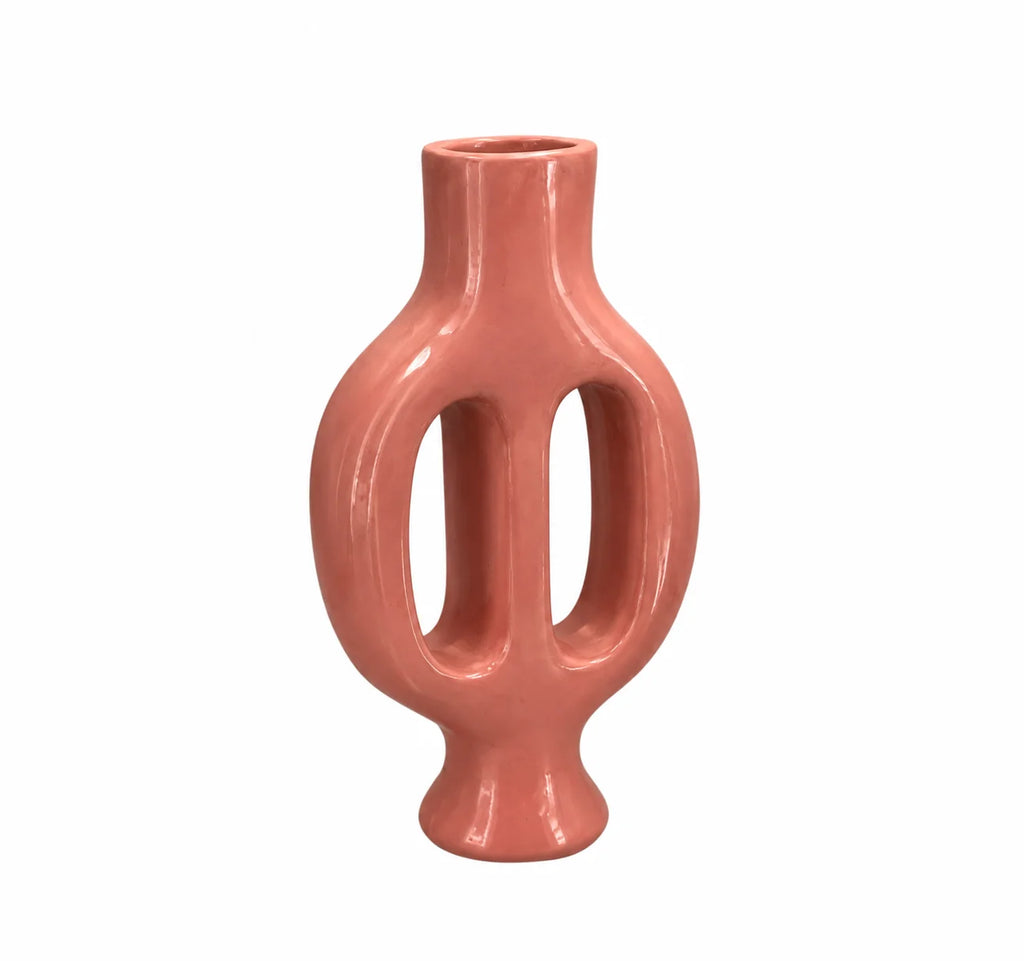 A glossy, sculptural ceramic vase in a muted terracotta pink color, featuring a bulbous body with two vertical cutouts and a short neck, set against a plain white background.