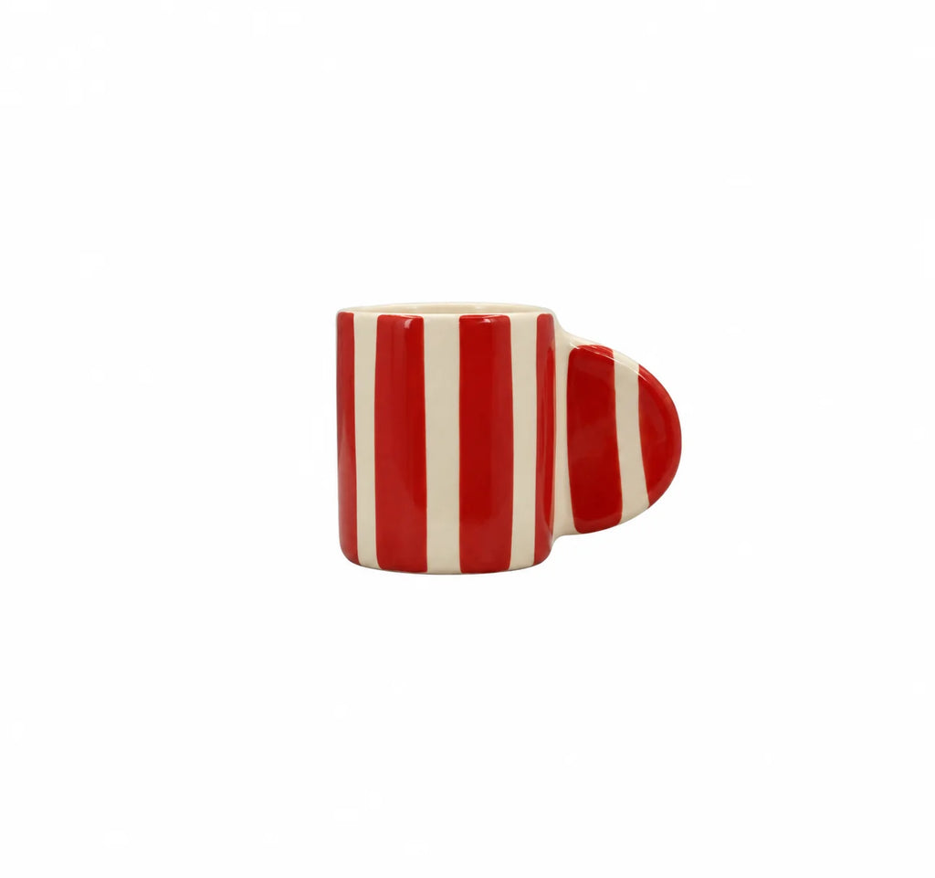A small ceramic mug with a bold red and off-white vertical stripe pattern, featuring a heart-shaped handle on the right side, set against a plain white background.