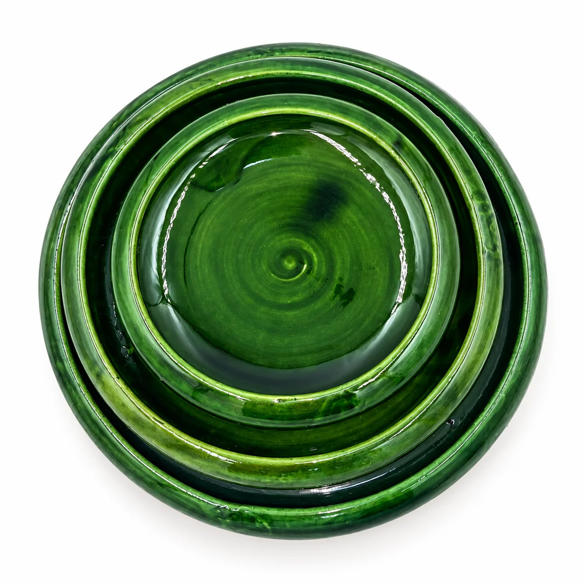 A set of three nested round ceramic plates in a glossy deep green glaze, photographed from directly above on a white background.