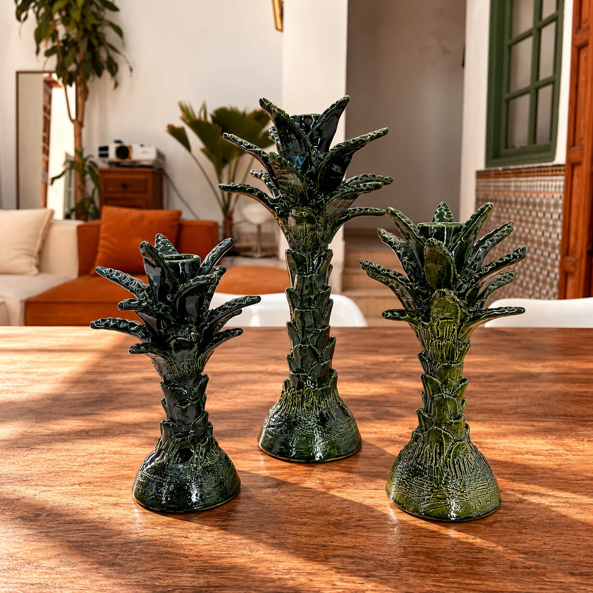 Three green textured ceramic decorative vases shaped like stylized palm trees, displayed on a wooden table in a warm, modern living room setting.
