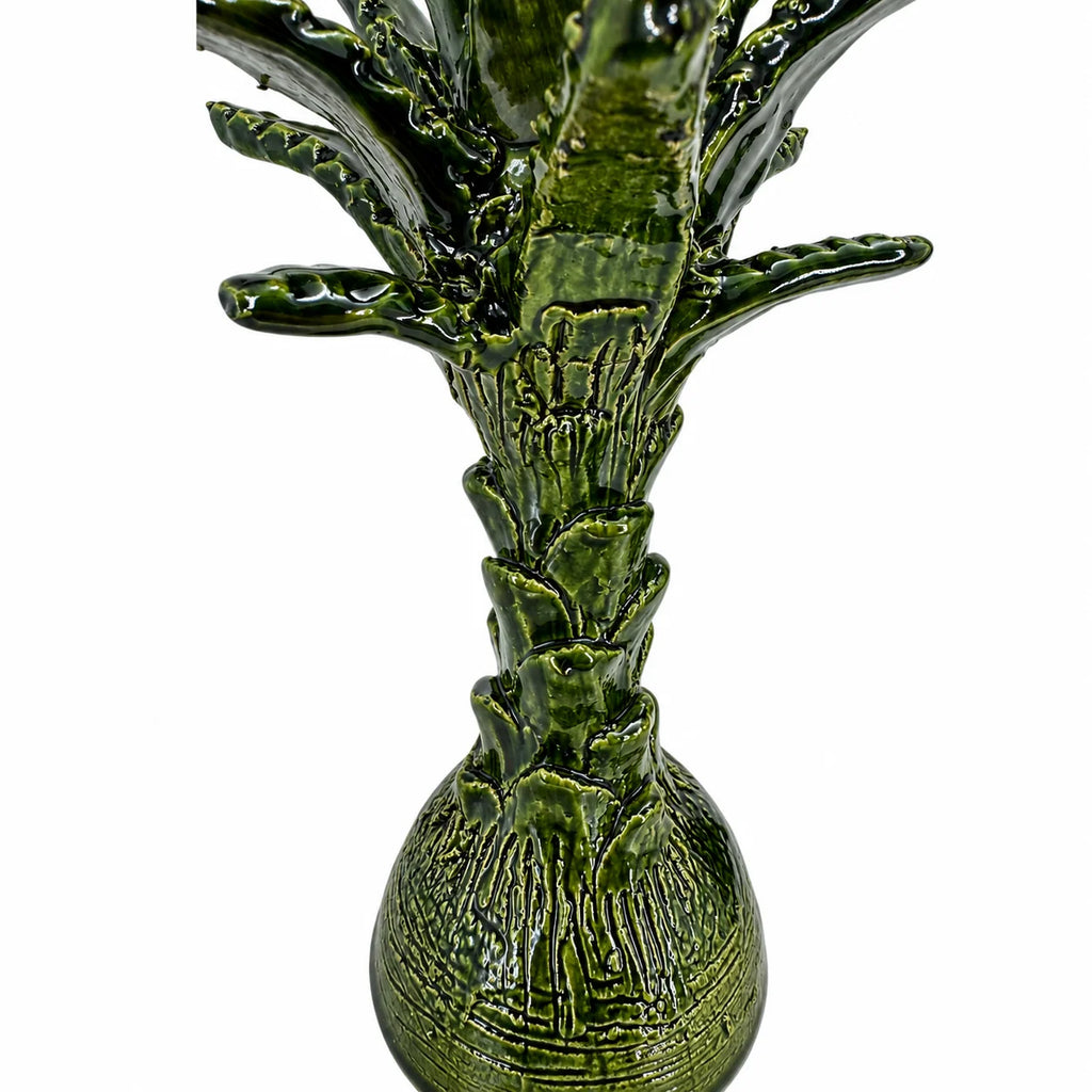 A glossy green ceramic pineapple figurine with textured, ribbed details and a rounded base, shown against a plain white background.