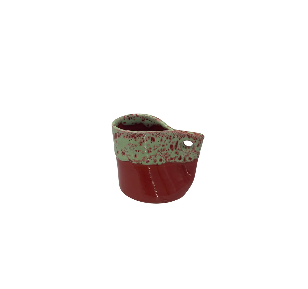 A small ceramic cup or planter with a glossy deep red body, a textured light green glazed rim, and a side cutout, shown on a plain white background.